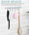 Side view of crevice cleaning brush and grout scrub brush on a gray wall-mounted hook rack with a pink loofah