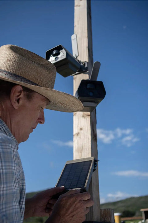 Man adjusting Run Forever Solar Panel With Built In High Capacity Battery For Trail Cameras on a wooden post outdoors.