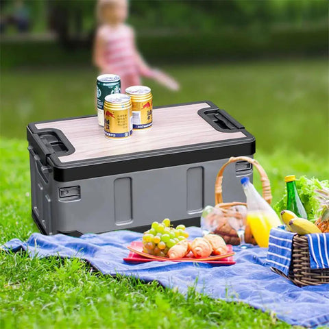 Kickass Folding Tailgate Crate Featuring Heavy Duty Wooden Tabletop Lid and Hella Massive Storage Volume for Smooth Car Camping Gear Organization and Rapid Trunk Setup In Matte Charcoal Black Coating holding drinks on picnic.