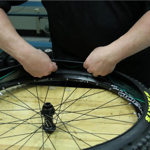 Person installing Bike Tire Liners And Protectors Lightweight Puncture Proof Set For 12 To 26 Inch Tires on a bike wheel.