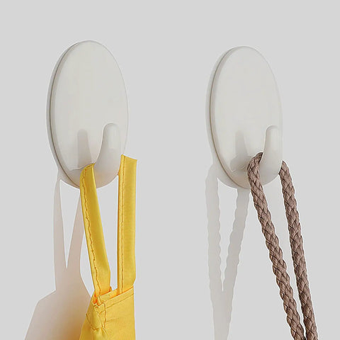 Heavy Duty Adhesive Wall Hooks For Bathroom And Kitchen Built Tough With Super Grip Oil Resistant Plastic Surface Mounts Zero Hole Punch Needed Fully Waterproof Set Of Three White Units holding a yellow strap and a brown rope.