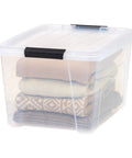32 Quart Clear Plastic Storage Bins With Easy Snap Lids stackable bin holding neatly folded sweaters for closet organization.