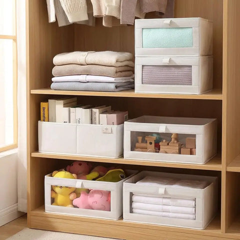4 Pcs Foldable Closet Storage Bins With Clear Window For Slick Organization And No Sweat Folding To Keep Your Wardrobe Tidy And Make Room Organization A Total Breeze on a wooden shelf with folded clothes and toys.