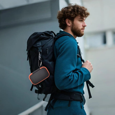Hard Case For SanDisk Extreme Portable SSD Built Tough Rugged Foam Padding And Mesh Pocket For USB Cables And SD Cards Custom Fit External Drive Protector In Bright Orange Zipper attached to backpack outdoors.