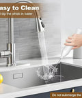 Person cleaning the rechargeable handheld milk frother with two stainless steel whisk heads under a kitchen sink tap.