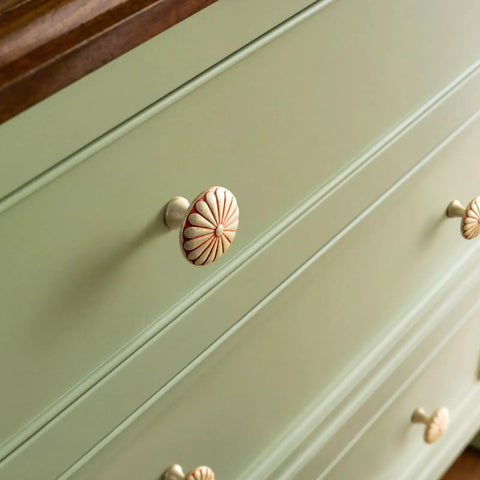 Close-up of 1.3 Inch Amber Red Cabinet Knobs on green dresser, featuring floral texture and zinc alloy design for kitchen furnishings.