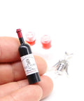 Hella Cool Miniature Red Wine Bottle Set Featuring two resin filled wine glasses and a static corkscrew for dollhouse decor, showing a hand holding a 38 mm wine bottle.
