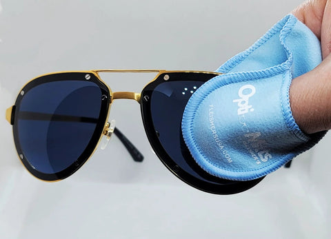 Sunglasses with gold frame and dark lenses being wiped by blue Opti-Mitts microfiber cleaning cloth.