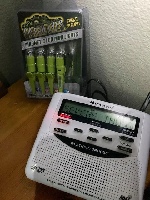 Weather radio next to packaging of Multi-Use Mini LED Lights 5 Pack With Magnetic Clip And Hands Free Design on wooden table