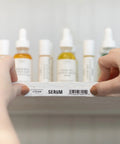 Hands holding a shelf labeled 'Serum' with the P Touch PT D610BT Label Maker With Bluetooth And USB Pro Grade Connected Label Printer.