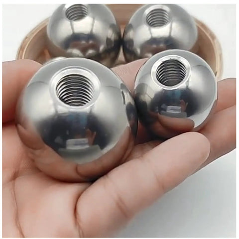 Stainless steel piercing replacement balls with M6 threaded holes, chrome spherical beads held in hand (close-up view)