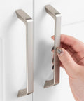 Hand holding 10 Pack 5 Inch Hole Centers Brushed Nickel Cabinet Pulls, zinc alloy hardware, installed on white cabinet