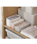 Slick Four Compartment Plastic Underwear Storage Box For Closet Dresser Drawers neatly organizing bras and leggings in a tidy closet.