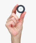 Hand holding a translucent puck mount for the Super Sleek Ski Wall Mount Rack Keeps Your Skis Tight And Scratch Free With Hybrid Edge Guard Tech.