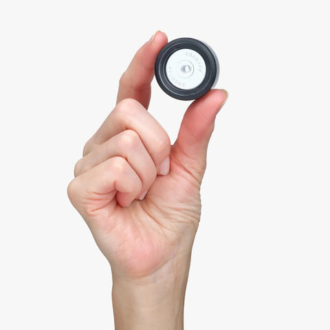 Hand holding a translucent puck mount for the Super Sleek Ski Wall Mount Rack Keeps Your Skis Tight And Scratch Free With Hybrid Edge Guard Tech.