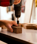 User driving Tough As Nails 2 Inch Deck Screws Gauge 8 for outdoor wood fences into wood with a drill at a workbench.