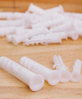 Heavy Duty White Plastic Expansion Tubes Smooth Install Drywall Anchors Rock Solid DIY Home Fasteners No Sweat Hollow Wall Plugs Easy Fix Self Tapping Hardware 100 Pack on wood background.