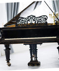 Antique black grand piano with ornate music rest and swivel casters, showcased in a bright indoor setting.