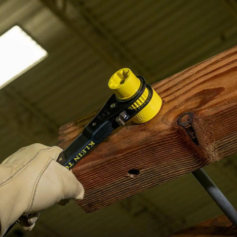 Six In One Lineman's Ratcheting Wrench With Bolt Through Design and Bright Yellow Socket on wooden utility pole
