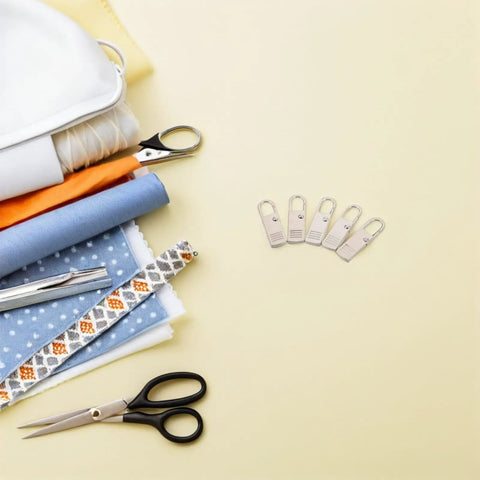Top Shelf Universal Replacement Zipper Pull Heads 20 Piece Metal Kit With Sleek Detachable Tabs For Backpacks Purses Jackets And Luggage Repairs That Are Pure Gold on a table with sewing materials.