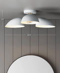 Modern ceiling light with three white dome shades, 5.9" high, 23.9" wide, mounted on a gray wood panel ceiling in a minimalist room.