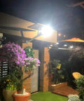 JUDYSSY Solar Floodlights illuminating a garden at night, highlighting flowers, plants, and outdoor decor.