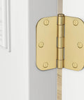 Close-up of a gold door hinge on a white interior door with visible screws, shown open to display hinge mechanism.
