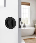 Matte Black Round Pocket Door Lock Set For Two One Eighth Inch Bore on white interior sliding door, bathroom background