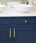 Premium Solid Metal Brushed Gold Cabinet Pulls on navy blue drawers beside white vessel sinks in modern bathroom.