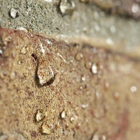 Close-up of water droplets on stone treated with One And A Half Gallon Clear Brick Sealer For Brick Stone Concrete And Masonry No Nonsense