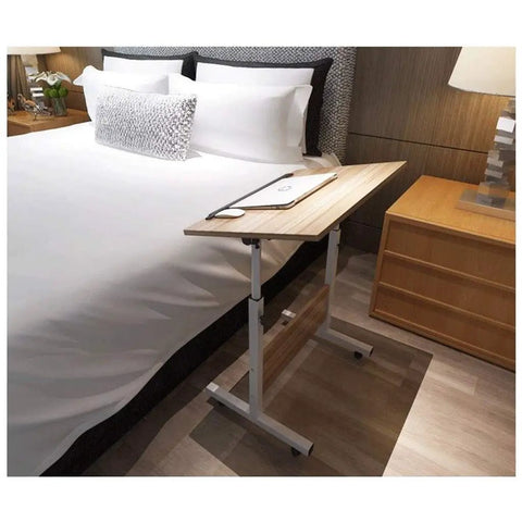 Adjustable Rolling Laptop Desk With Locking Castors Portable Computer Stand placed beside a bed for comfortable use.