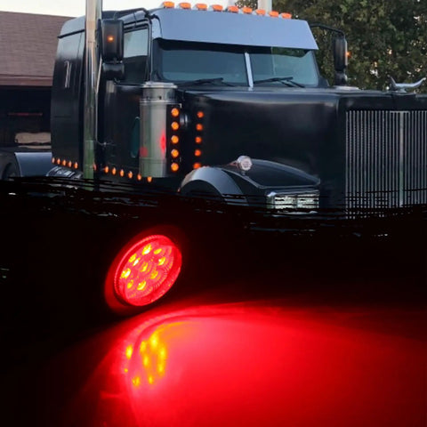 Ten Pack Two Inch Round Red LED Trailer Side Marker Lights Kit With Clear Lenses illuminated in front of a black truck at dusk