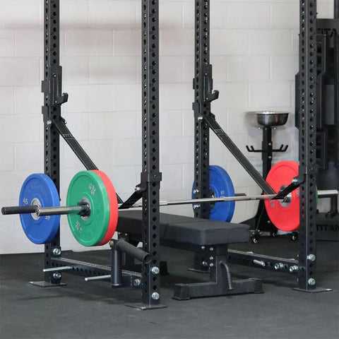 Hardcore Power Rack Safety Straps Rated Five Thousand Pound With Bounce Free Catch Tech Built From Beefy Nylon Webbing For Dead Silent Drops And Knurl Guard Coverage Home Gym Flex Essential Set Of Two attached to a power rack with weights.