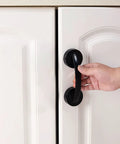 Black Suction Cup Glass Door And Window Handle attached to a white cabinet door, demonstrating no-drill installation, supports up to 22 lbs.