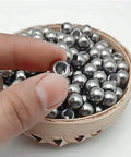 Stainless steel piercing replacement ball with M8 threaded hole; small silver sphere in wooden bowl
