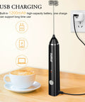 Handheld Milk Frother USB Rechargeable Electric Foam Wand for Coffee Nerds charging on a countertop next to a latte