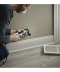 Man using Pro Grade Corded Oscillating Multi Tool Kit 120V 3.5 Amp Power, Reconditioned, for cutting wall near floor vent