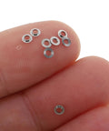 One Hundred Pack Stainless Steel Eyeglass Flat Washers For Glasses Frame Repair Kit Screw Gaskets and Spacer on a fingertip.