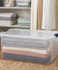 66 Quart Clear Plastic Storage Bin With Secure Blue Latch Lids Stackable Home Organization Tote For Garage Closet And Pantry with folded blankets inside.