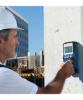 Heavy Duty Handheld Wall Scanner And Stud Detector used by a worker on a concrete wall to locate wood studs and metal pipes.