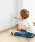 Baby reaching for Toggle Style Wall Switch Guard For Kidproof Home Safety Clear Light Switch Cover installed on wall