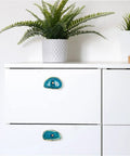 Top Tier Agate Cabinet Drawer Knobs With Stunning Gold Plated Edges on white dresser with potted plant.