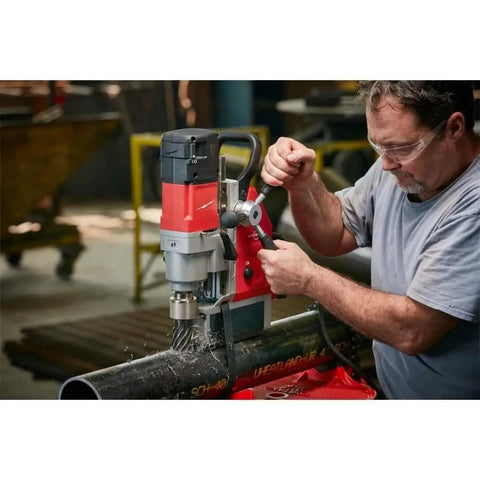 1-5/8 Inch Corded Magnetic Drill Kit With Variable Speed Control in use on steel pipe for precise hole drilling.