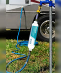 Heavy Duty Catalytic Carbon KDF Inline RV Water Filter attached to a water source with a blue hose on grass.