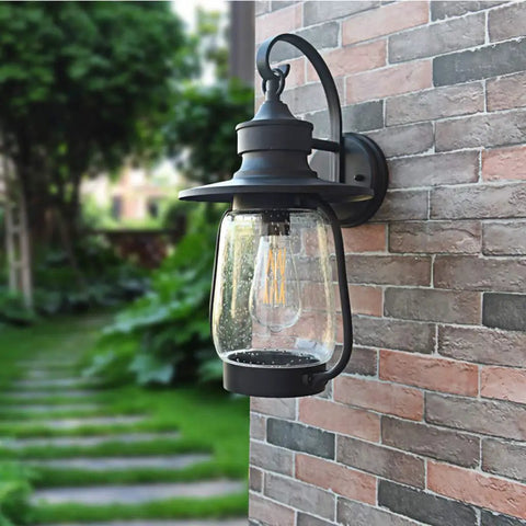 Rock Solid Outdoor Wall Lantern With Slick Industrial Design And Transparent Bubble Glass Shade Featuring A Top Shelf Led Filament Bulb mounted on a brick wall.