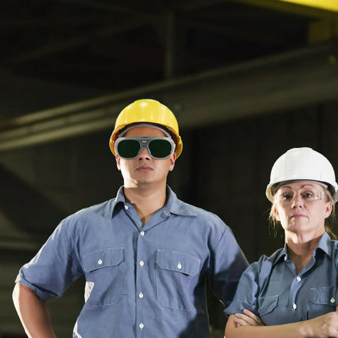 Heavy Duty Pair Of Welding Goggles With Double Layer Plastic Lens worn by workers in a shop setting for safety during tasks.