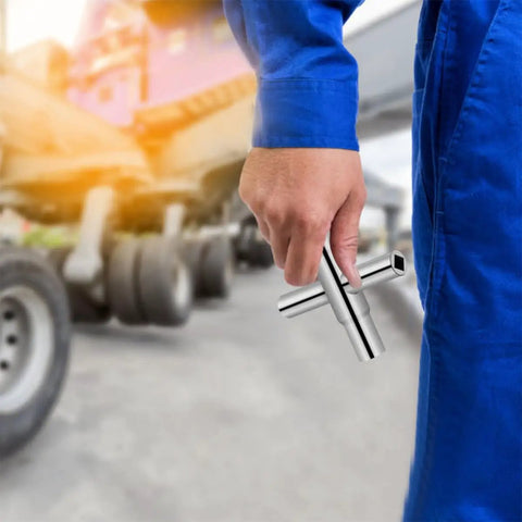 Hand holding a Heavy Duty 4 Way Socket Wrench And Water Valve Key Set for outdoor faucet nuts in a yard.