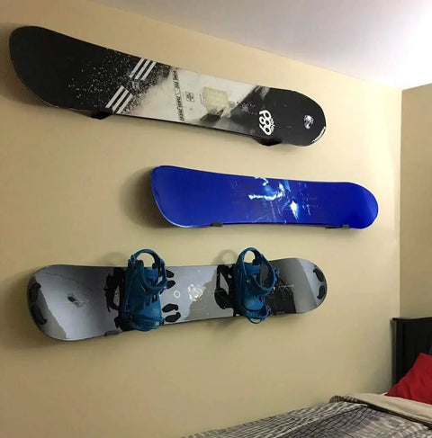 Rock Solid Aluminum Wall Mount Snowboard Rack With Hella Secure Eva Grip Pads holding three snowboards and bindings on a wall.