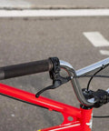 Close-up of red bike handlebar with brake lever, featuring All In One Universal Bike Cable Replacement Kit for Shifting and Braking.