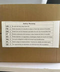 Safety warning label in multiple languages on a brown cardboard box